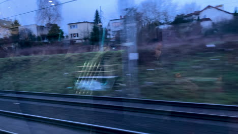 reflections of a person in face mask through the window glass of a traveling train during daytime