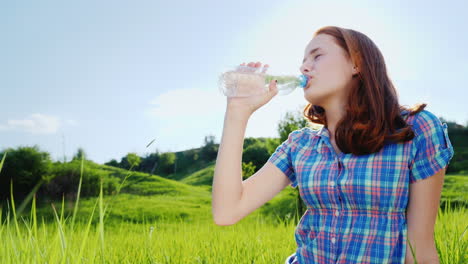 a teenager drinks clean water from a bottle on a picnic in a picturesque place 1