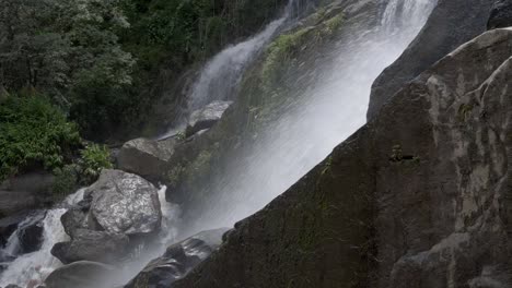 water spray from fast flowing waterfall over rocky boulder terrain