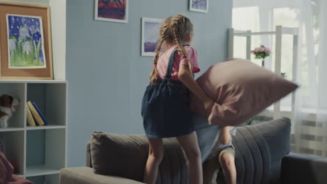 happy elder sister and brother have pillow fight at home