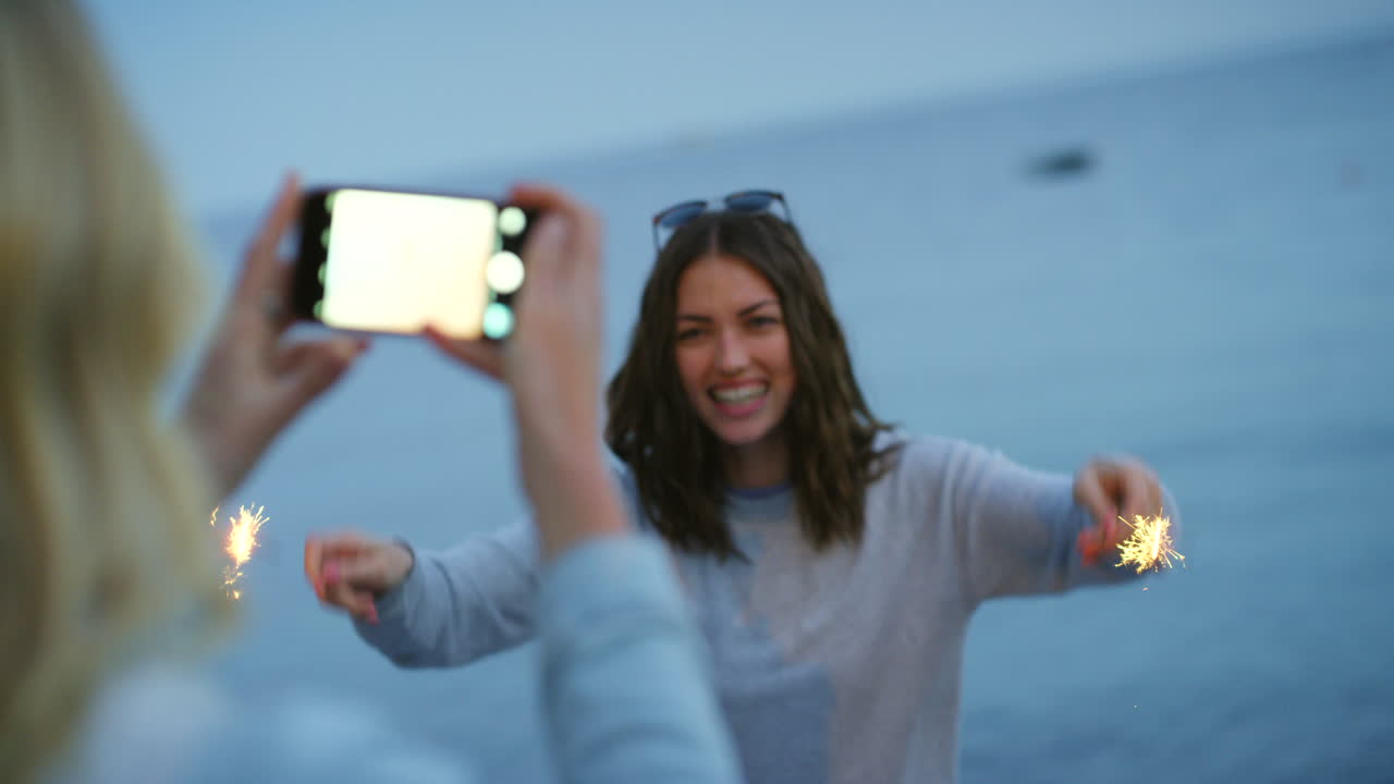 amigos tomando fotos en la playa al atardecer con chispas