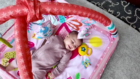 six month old south asian baby girl lying on a colorful playmat, having fun with toys