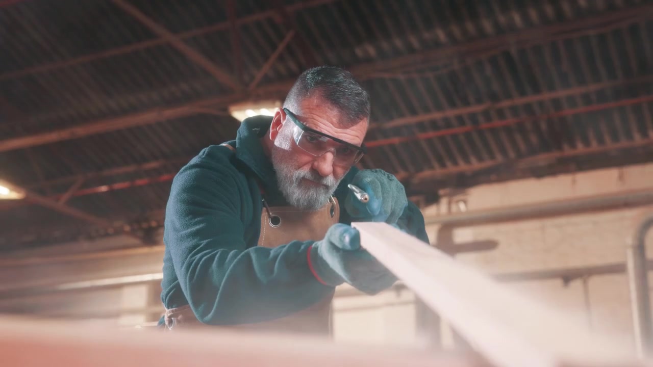 Carpenter Using Air Blower to Clean Wood Plank in Workshop