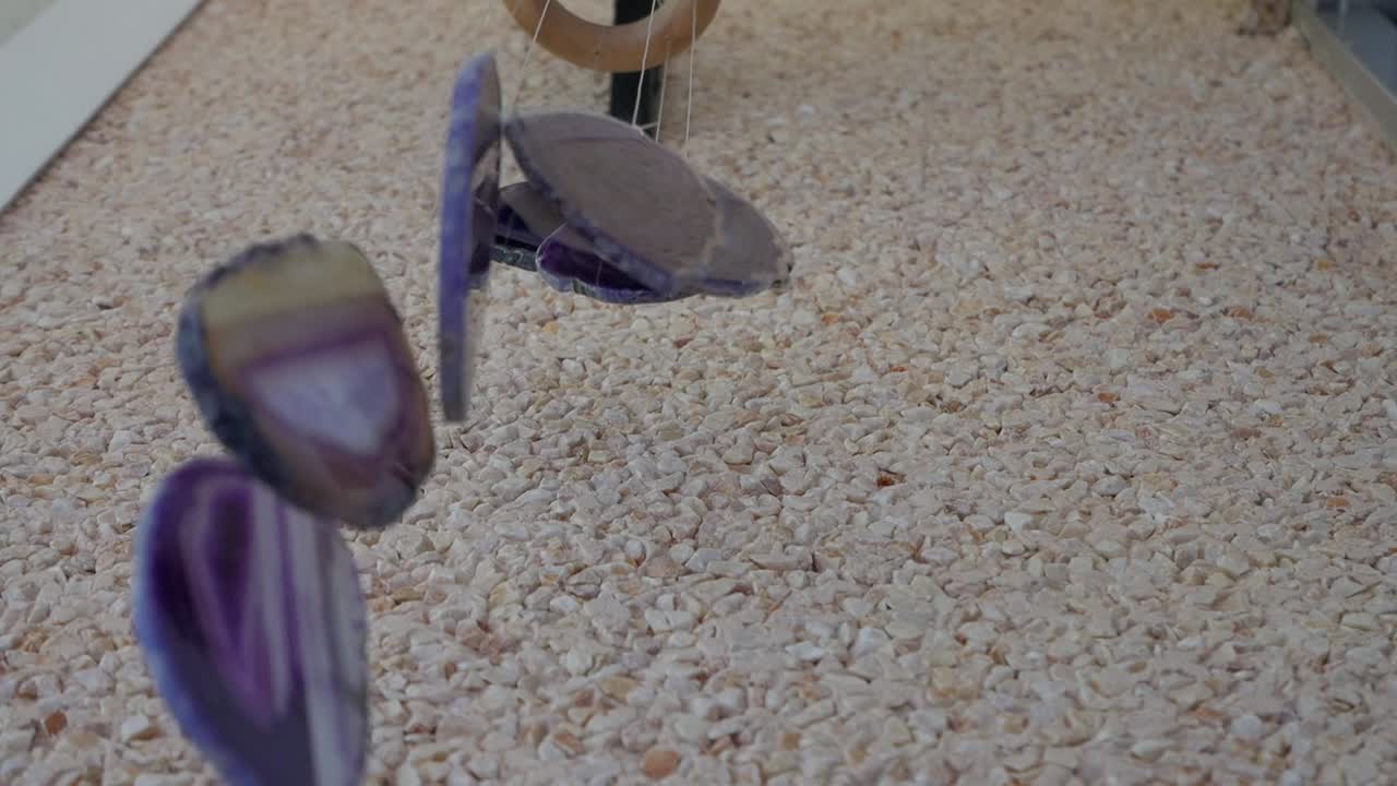 Coastal wind chimes gently swing over gravel surface, evoking calm