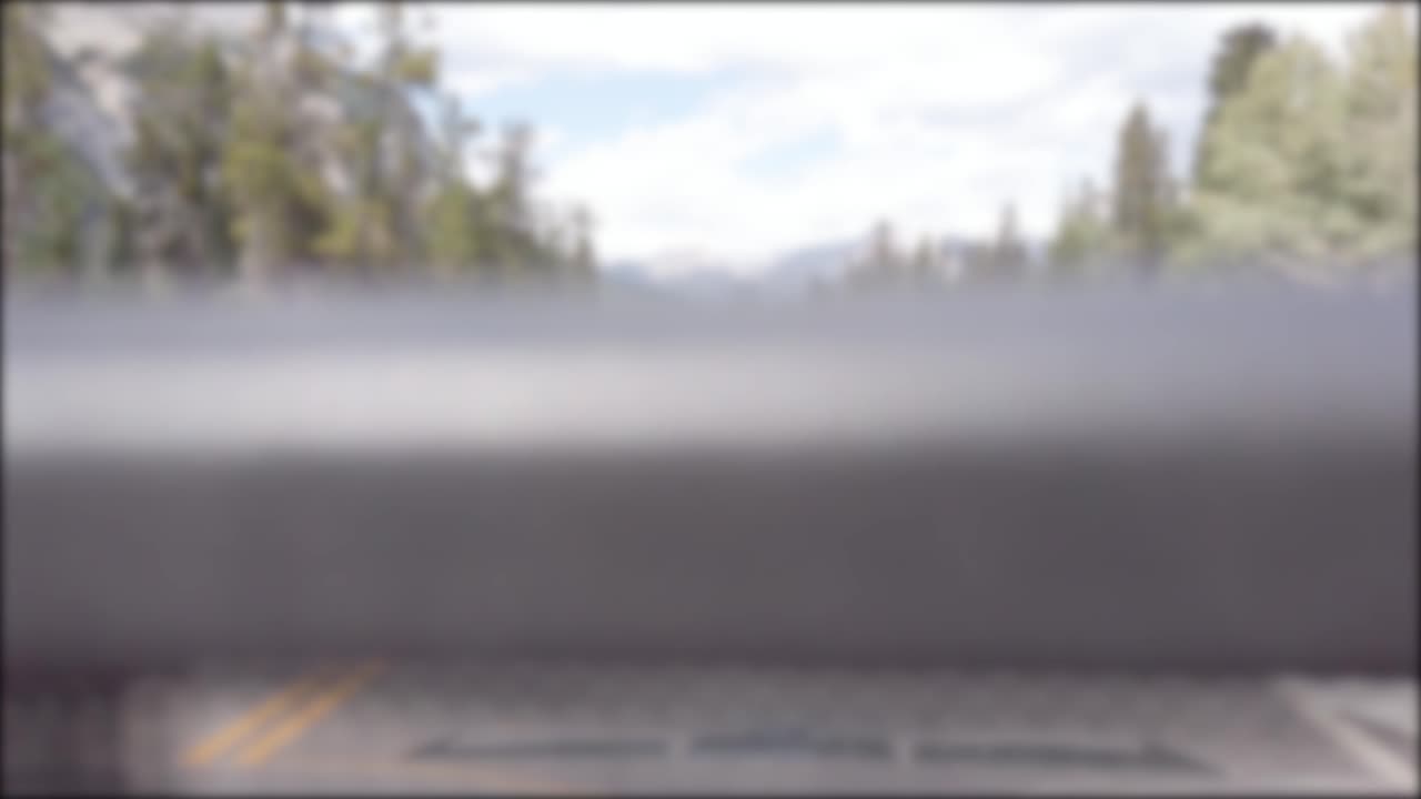 Blurred-out of focusing technique view from the moving car while driving along the local natural way in canada with natural view of Mountain range and pine tree forest in summer holiday