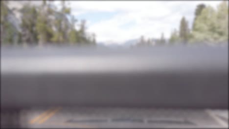 blurred-out of focusing technique view from the moving car while driving along the local natural way in canada with natural view of mountain range and pine tree forest in summer holiday