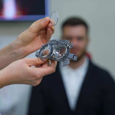 an eye doctor is going to check the eyesight and puts different lenses in special glasses for a young man. young man on blurred background