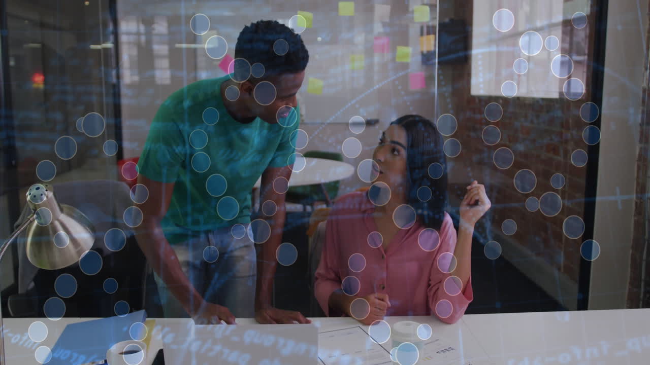 Discussing work at desk, two colleagues using animation with data visualization