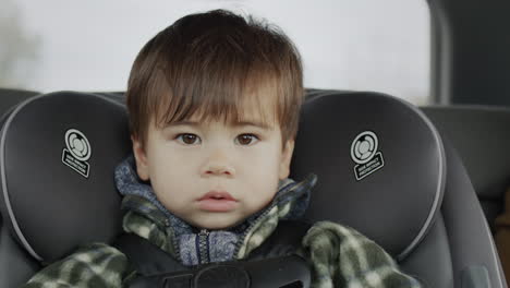 portrait of a serious young passenger of two years. rides in a child car seat