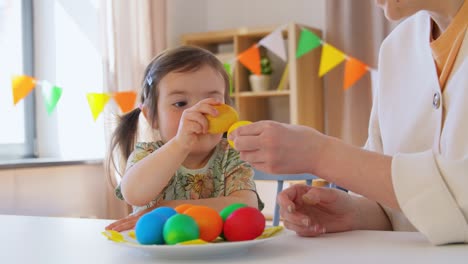 niña y madre golpeando huevos de pascua en casa
