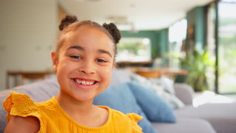 Portrait-Of-Smiling-Girl-Relaxing-Sitting-On-Sofa-At-Home