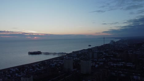 Paisaje-Panorámico-Aéreo-Del-Atardecer-En-La-Ciudad-Costera-De-Brighton,-East-Sussex,-Muelle-De-Agua-De-Mar-En-Contraste-Al-Atardecer