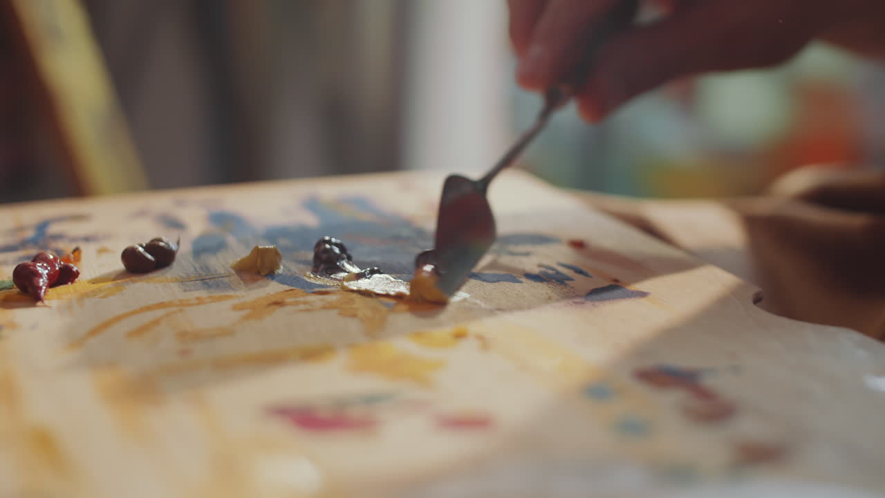 manos de un artista mezclando colores de pintura con un cuchillo de paleta