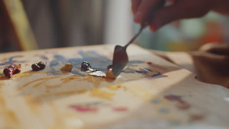 hands of artist mixing paint colors with palette knife