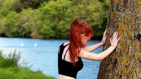 fit redhead warming up against a tree