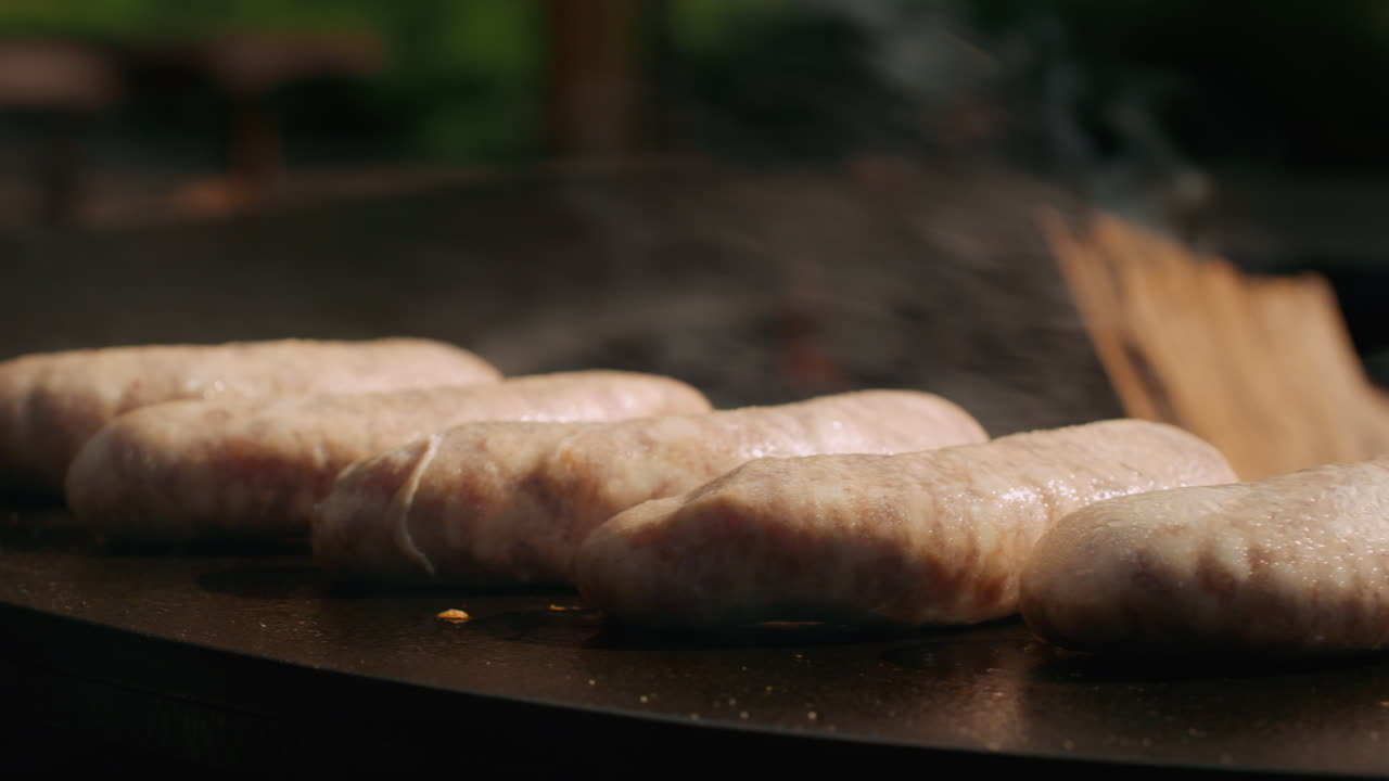 hombre usando fórceps en la parrilla al aire libre. hombre girando salchichas en la parrilla