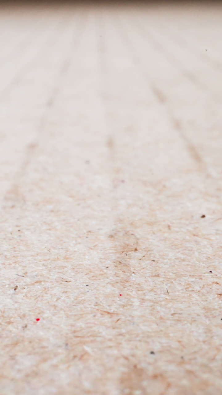 Motion along large blank brown cardboard sheet at bright light extreme close view. Corrugated packaging paper. Wrapping recyclable material