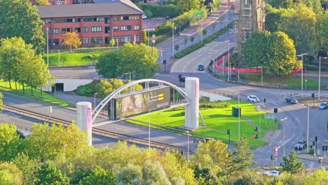 large electronic billboard over a road in manchester on a sunny day