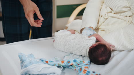 padres cambiando la ropa del bebé recién nacido en el hospital