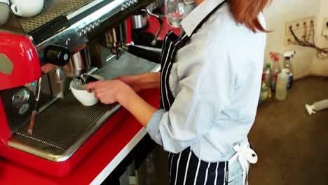 camarera haciendo una taza de café en el mostrador