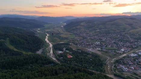un disparo de avión no tripulado captura la ciudad de gura humorului al atardecer con el río moldavia y un pájaro volador