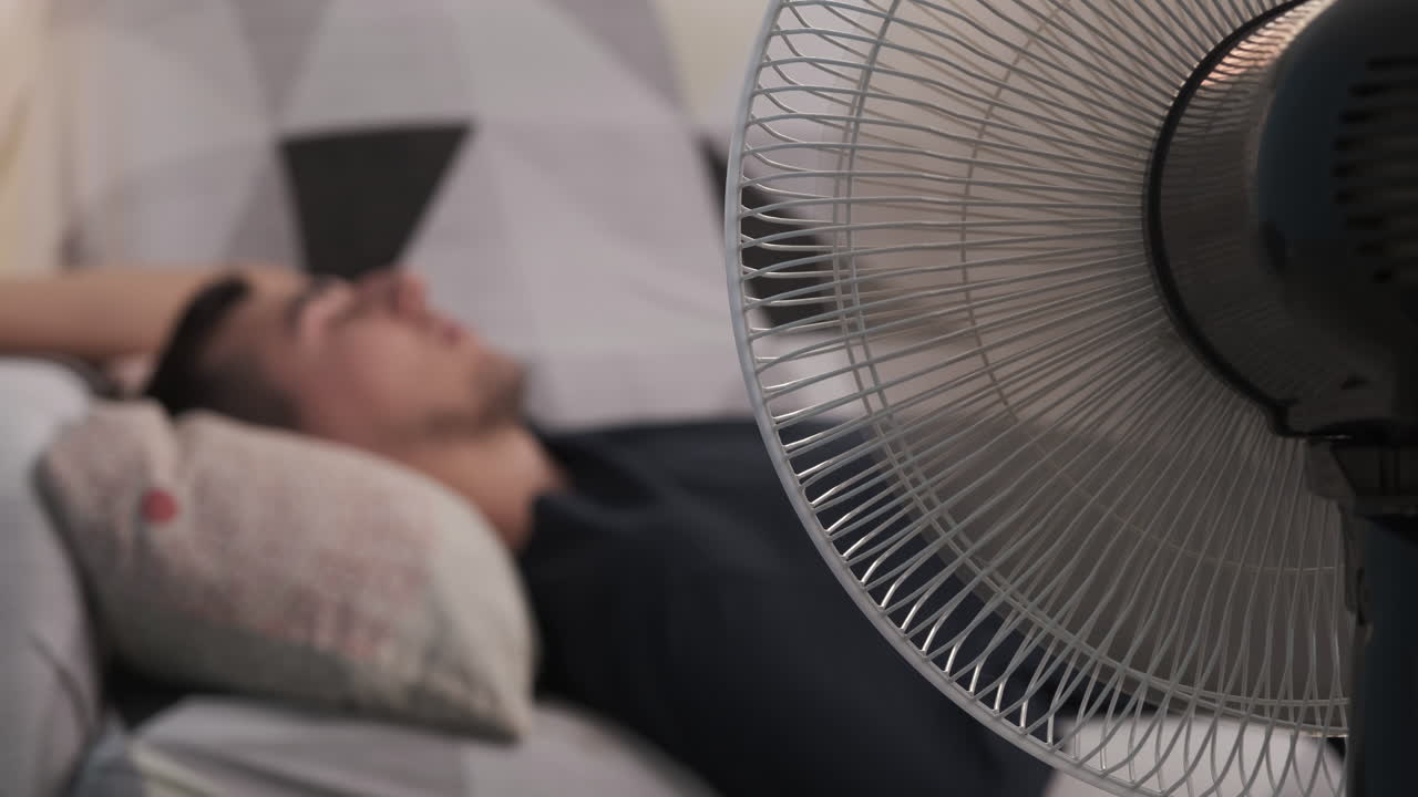 Man relaxing in front of a fan during hot weather