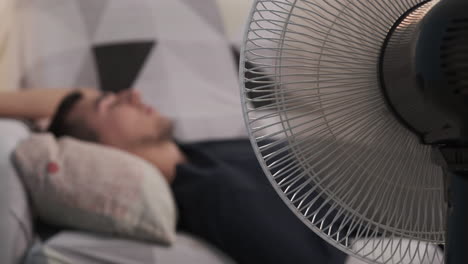 man relaxing in front of a fan during hot weather