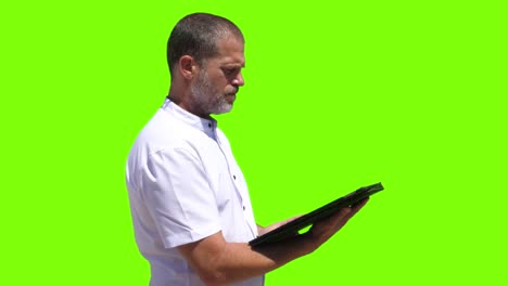 A-person-aged-40-interacts-with-a-tablet,-tapping-on-it,-and-subsequently-activates-a-virtual-button-visible-on-a-green-screen