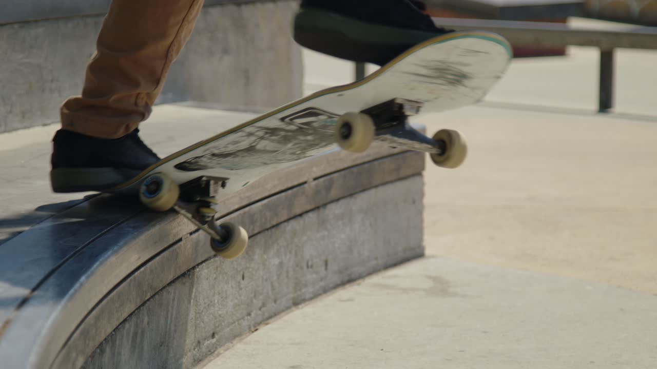 Close-up shot of a skateboarder performing a grind on a concrete ledge at the skatepark