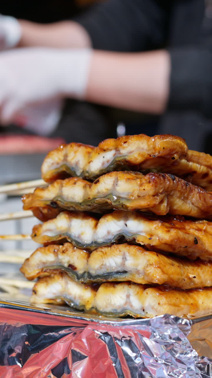 Close up of grilled fish on skewers at the Tsukiji Fish Market in Chuo, Japan. Vertical