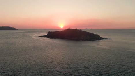 aerial reveal shot of sunset behind dark costa rica island