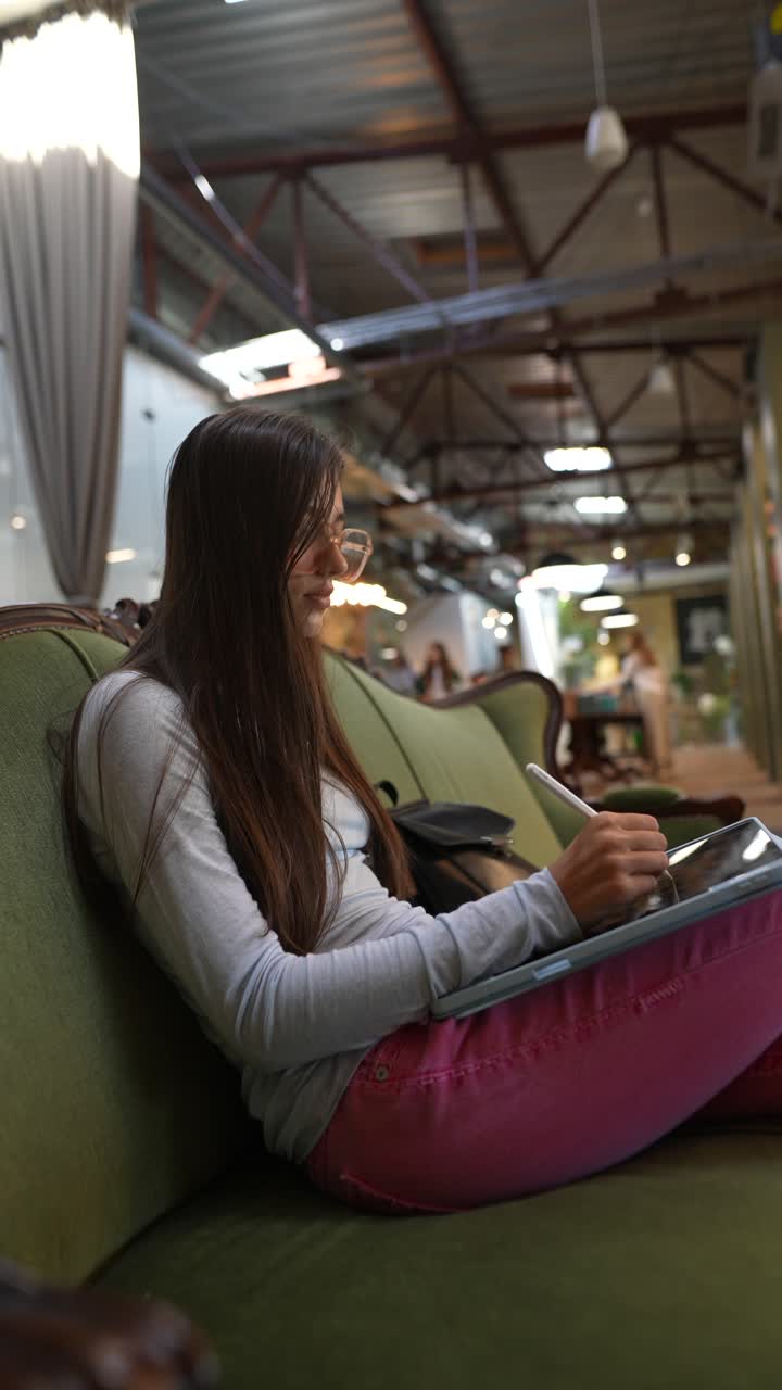 una mujer joven dibujando en una tableta en un café