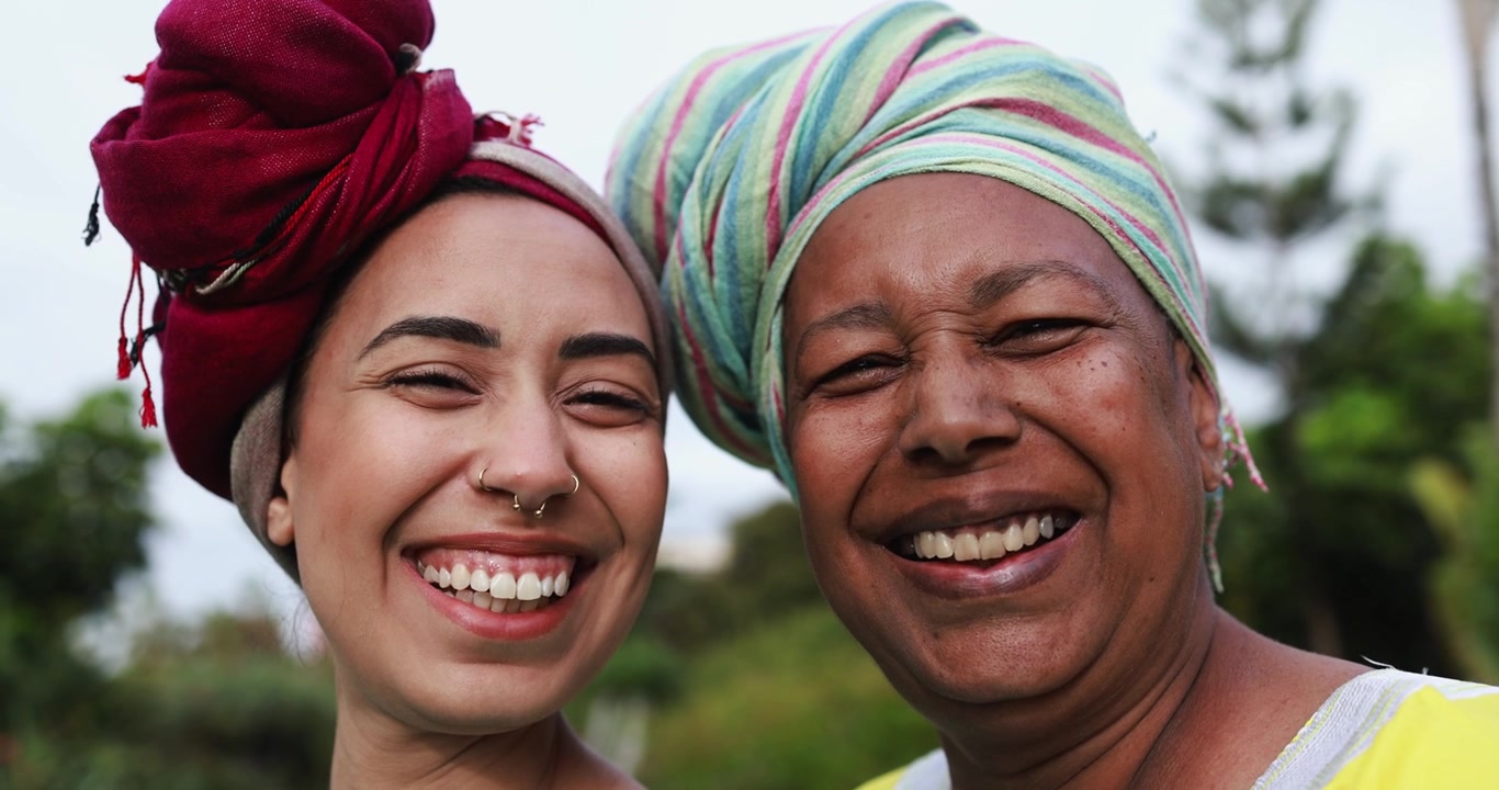 Dua Wanita Beragam yang Bahagia Mengenakan Penutup Kepala dan Tersenyum