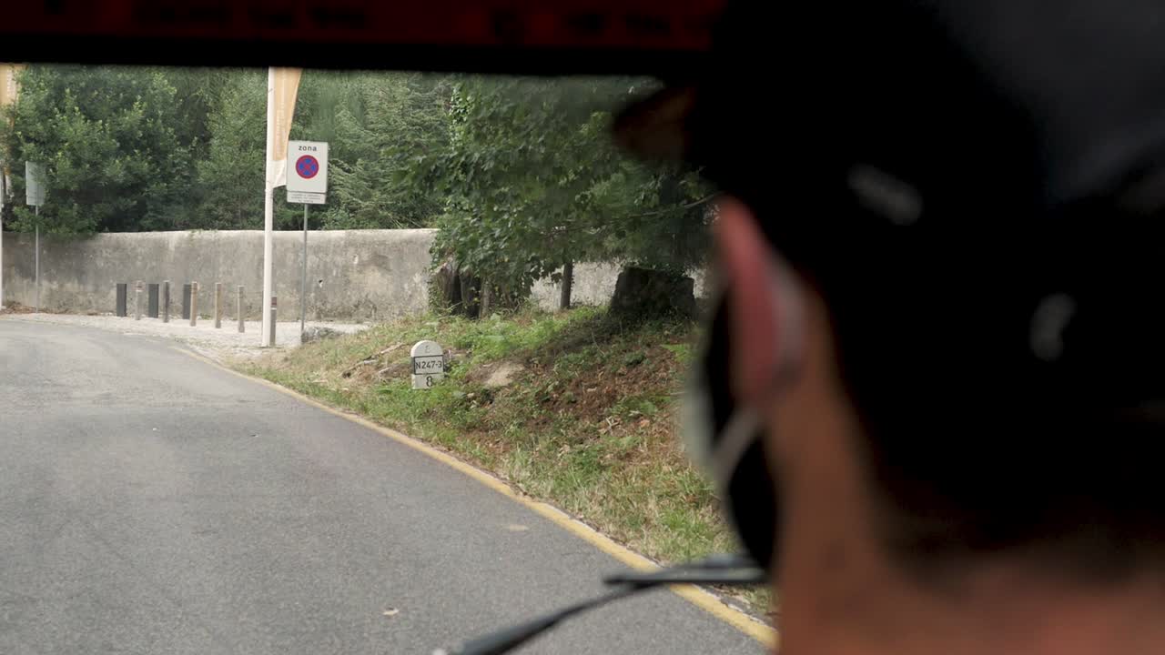 Slowmotion of a tuk tuk (auto rickshaw) view in Sintra, Portugal. The driver is wearing a mask for covid protection.