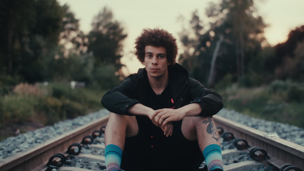 Man Sitting on Train Tracks
