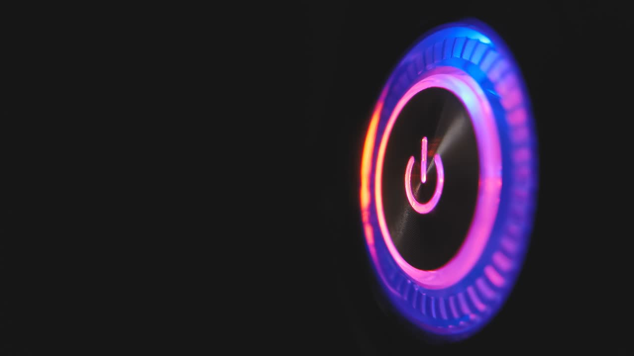 un bucle de video macro de 4k de un botón de encendido de la computadora en la unidad del sistema sobre un fondo negro.