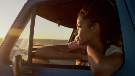 mujer apoyada en la ventana de una camioneta pickup en la playa 4k