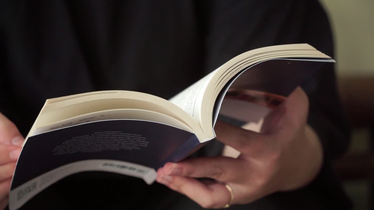 Focused hands turning pages of a book, perfect for themes of education, personal growth, or quiet lifestyle