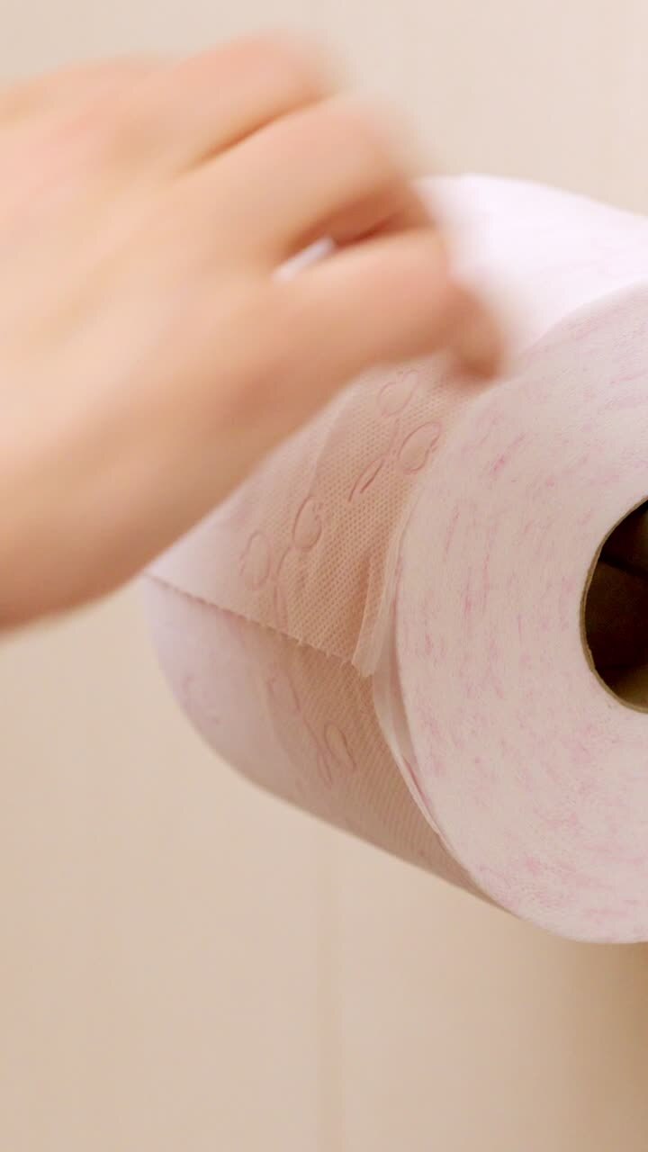 Man pulls sheets from toilet paper roll in bathroom