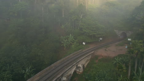 pullback establishing shot of nine arches bridge and tunnel on misty and sunny morning in ella sri lanka