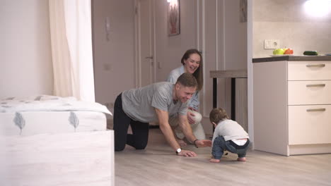 distant view of parents playing with their baby on the floor at home