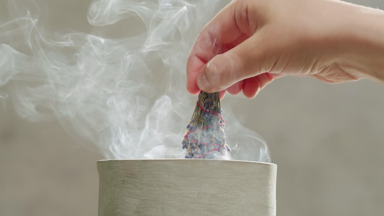 Person holding Palo Santo wood stick in hand, aromatic Palo Santo burning on black background, smoke spreading around, slow motion video clip, high quality 4k close up footage. High quality 4k footage