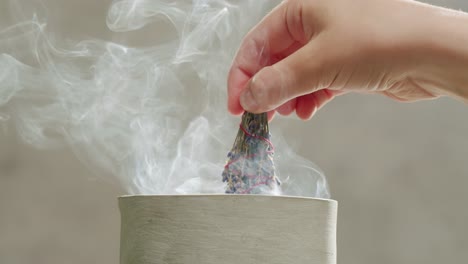 person holding palo santo wood stick in hand, aromatic palo santo burning on black background, smoke spreading around, slow motion video clip, high quality 4k close up footage. high quality 4k footage