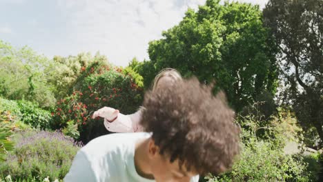 Happy-diverse-couple-playing-in-garden-on-sunny-day