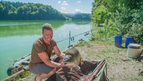 Pescador-Mostrando-Una-Carpa-Que-Atrapó-En-Un-Lago,-Sosteniéndola-Con-Orgullo-Con-Las-Manos