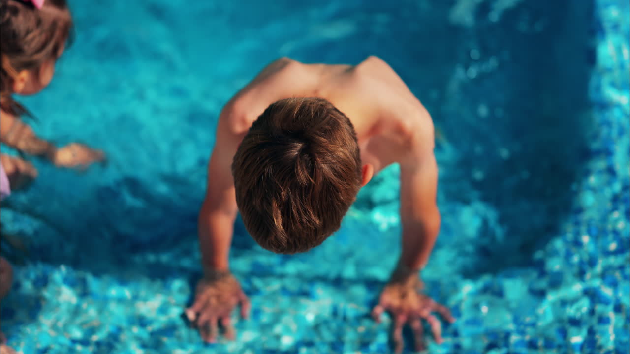 Foto dall'alto di un bambino e una bambina che giocano in una piscina blu brillante
