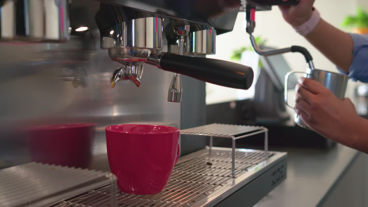 Barista che utilizza una macchina da caffè espresso per riempire una tazza e montare il latte per un latte macchiato in un bar, spazio per il testo