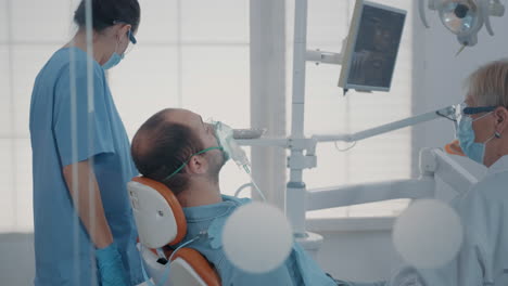 dental assistant using oxygen mask to do anesthesia on patient