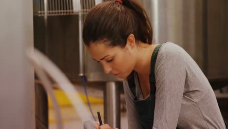 worker maintaining record on clipboard in factory