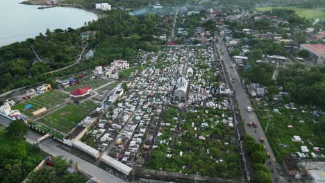 panoramic aerial orbit of catholic cemetery and memorial alongside rural village town in catanduanes, philippines during daytime